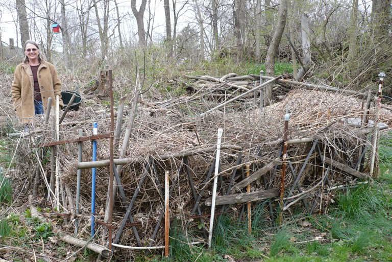 Anna and her compost bin, which she created “free-hand” with odd broom sticks, twigs, mop handles, rusty pipes, and other finds.